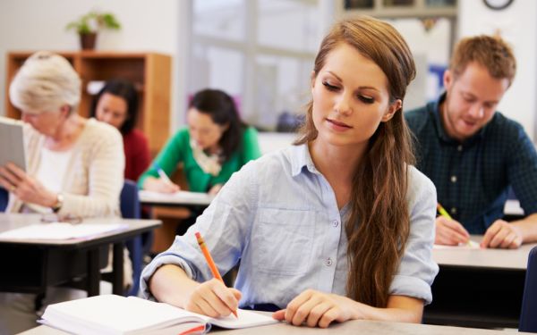 Image showing woman writing in a notebook in a classroom